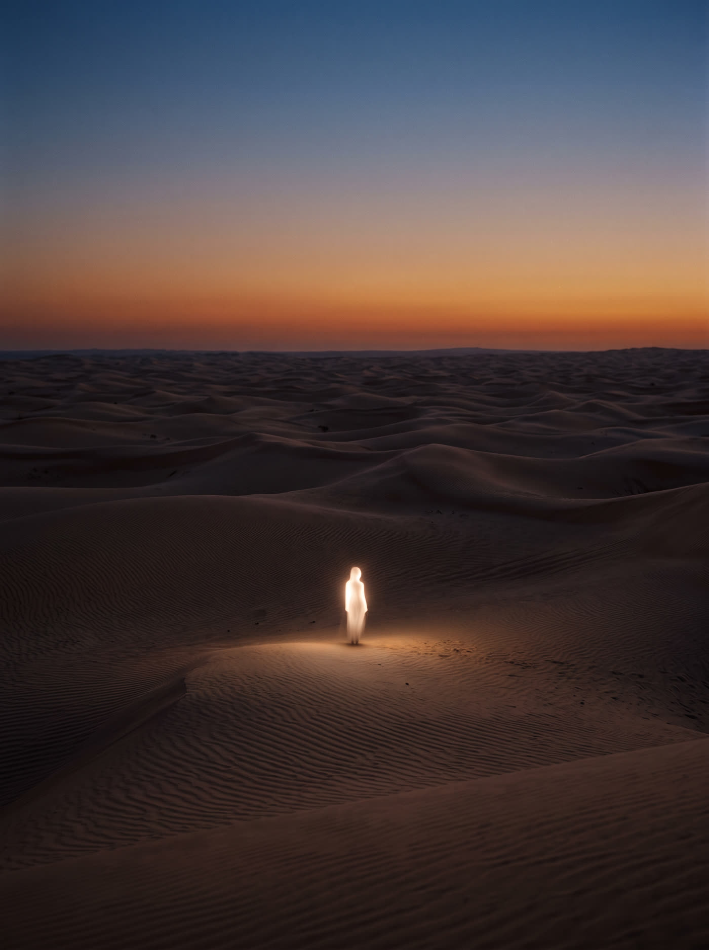 Vast dusk sand dunes with a single luminous figure casting light across the sand